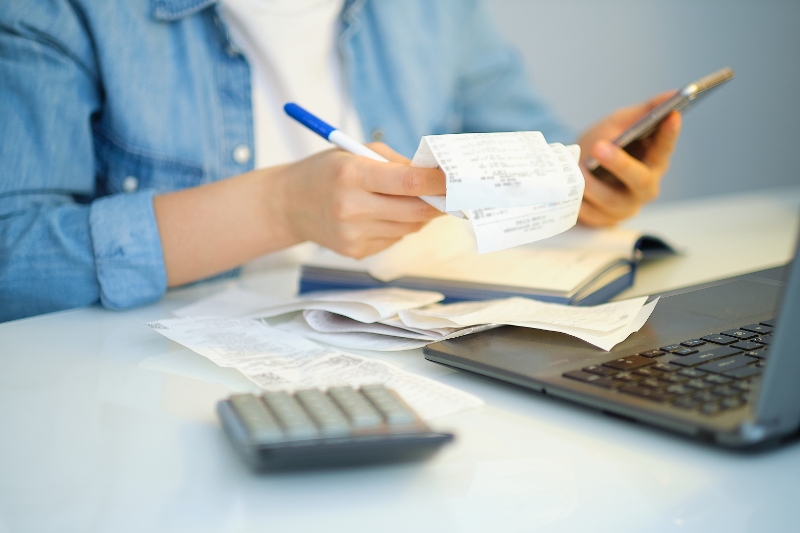 Woman holding receipts and computing expenses