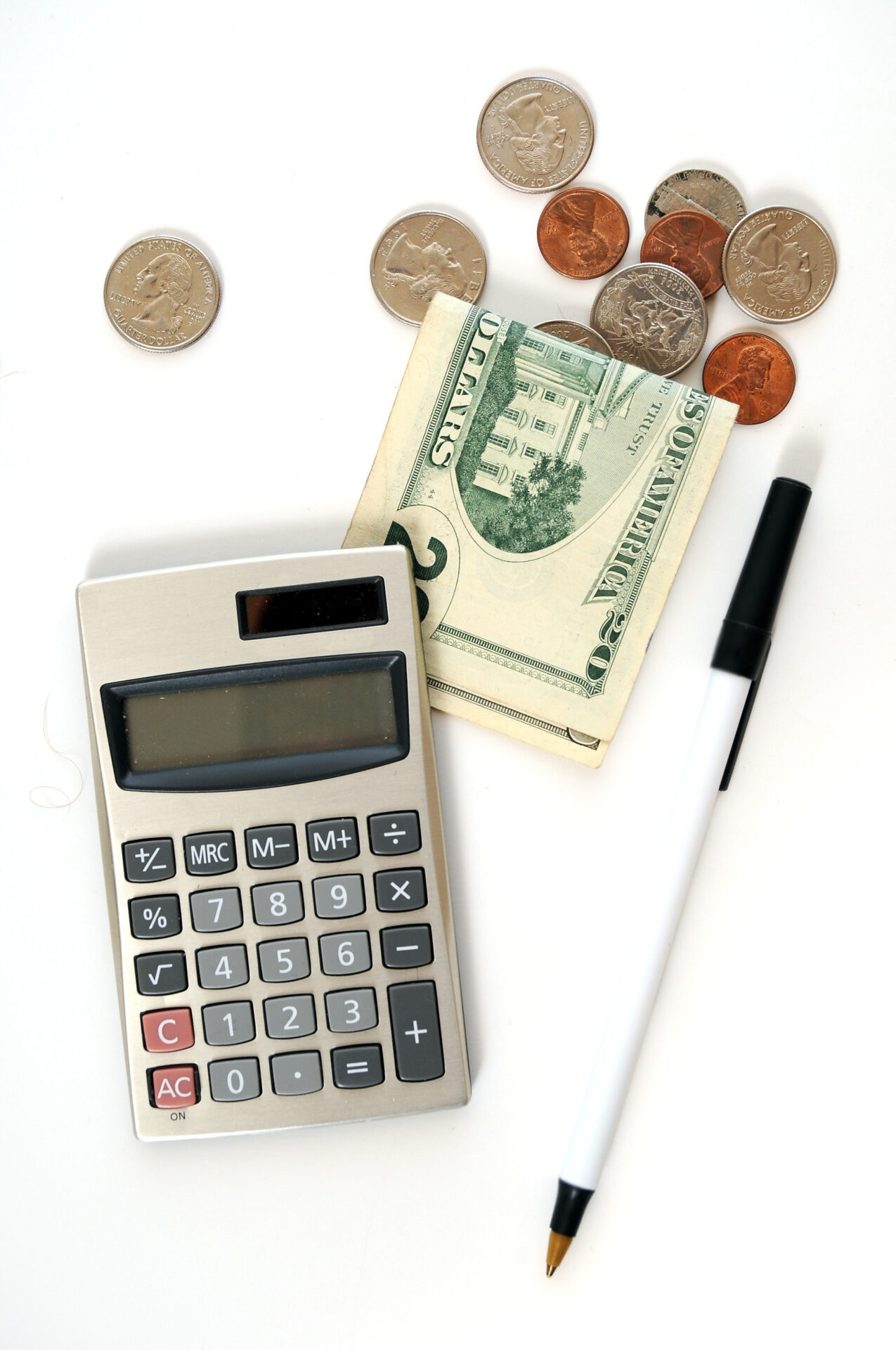 Calculator surrounded by various coins and bills, illustrating financial calculations and money management