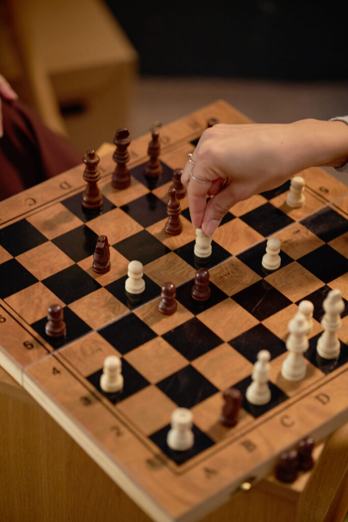 Close-up of hands strategically moving chess pieces on a wooden board during an indoor match