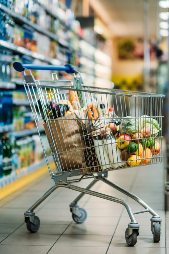Close-up of a shopping cart containing purchases, showcasing items in a supermarket setting.