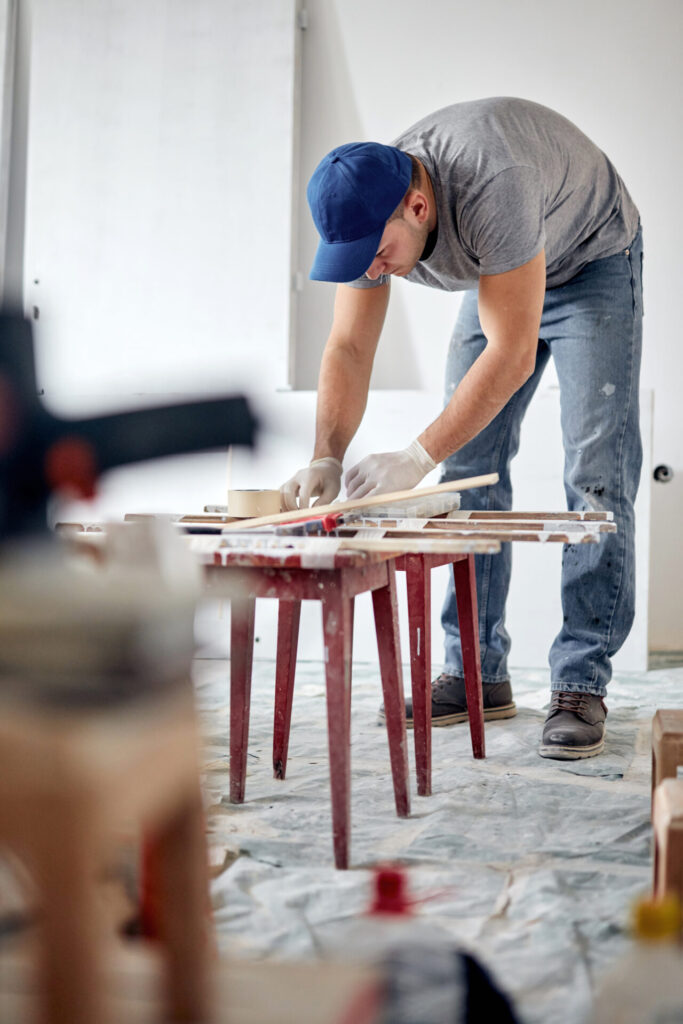 Young man engaged in a DIY budget renovation project in his new apartment, surrounded by tools and materials