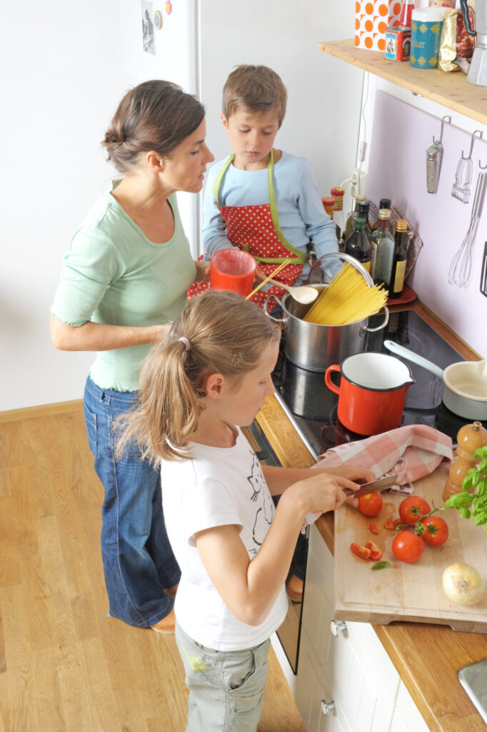 Family of three joyfully cooking together in a bright kitchen