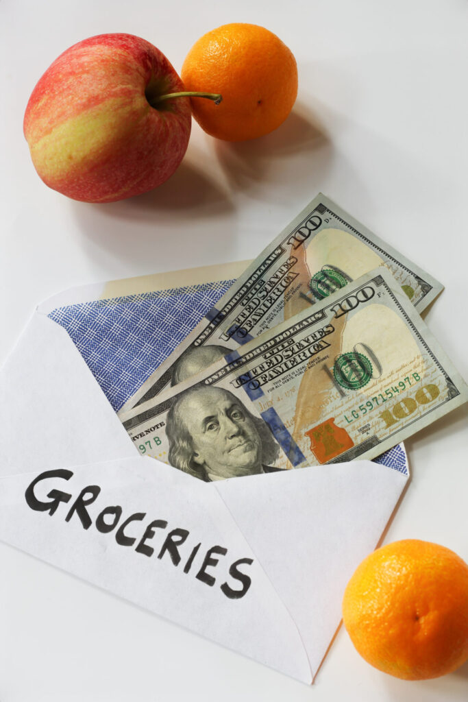 Grocery budget envelope containing several 100 dollar bills, illustrating a budgeting concept for grocery expenses