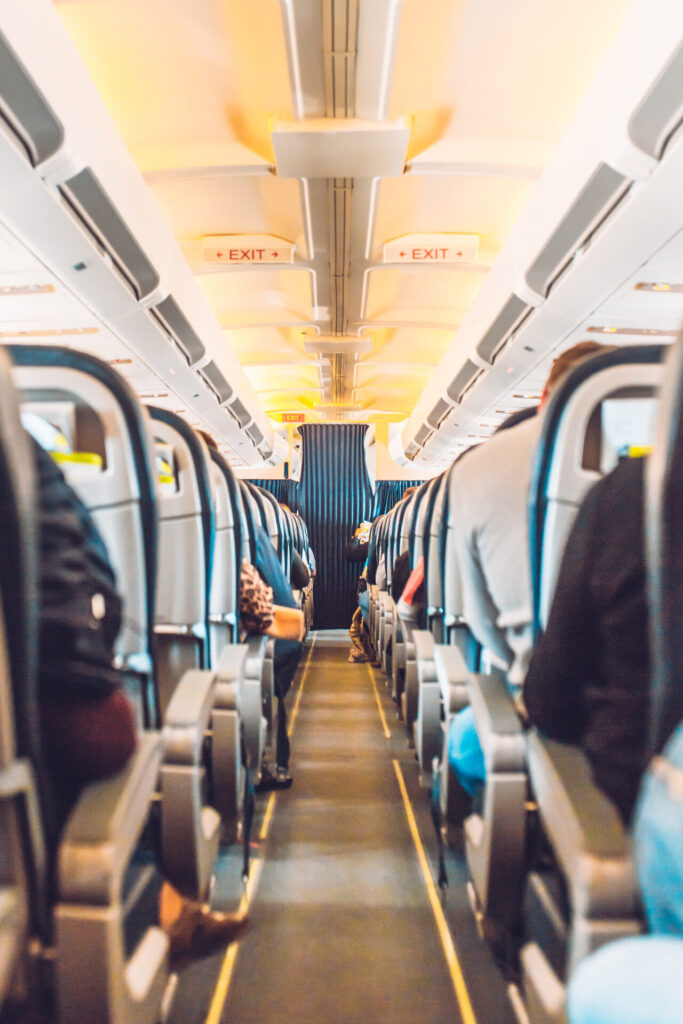 Narrow aisle between rows of economy class seats on a low-cost airline cabin