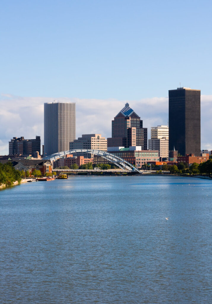 Rochester, New York skyline with a river and bridge, highlighting the city's blend of nature and urban development.
